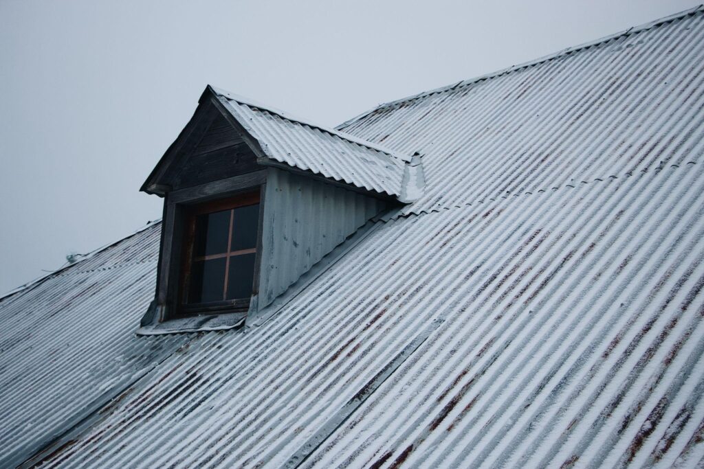 damaged surroundings of chimney or vents of metal roof with a small dormer window.